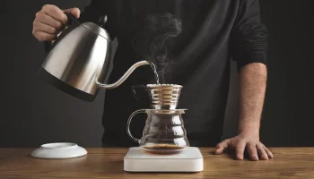 spills-hot-water-prepare-filtered-coffee-from-silver-teapot-beautiful-transparent-chrome-drip-coffee-maker-white-simple-weights_346278-1316